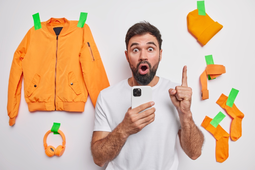 shocked-handsome-man-with-thick-beard-keeps-index-finger-raised-got-brilliant-idea-holds-mobile-phone-online-communication-poses-against-white-background-plastered-clothes-accessories.jpg
